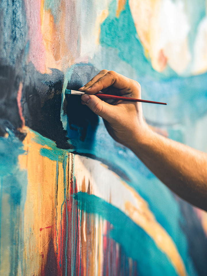 hand with paint brushes creating art